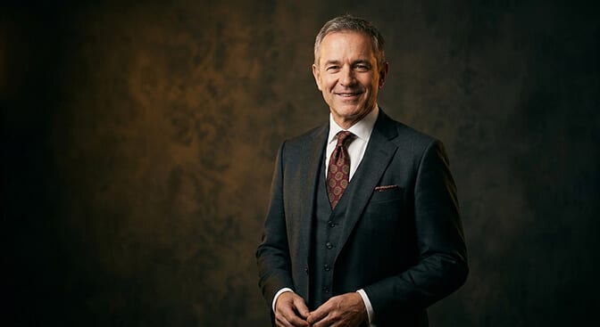 Warm executive headshot style with approachable expression warm lighting and natural shoulder framing